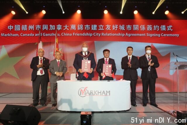 A group of men standing on a stage with a sign Description automatically generated with low confidence