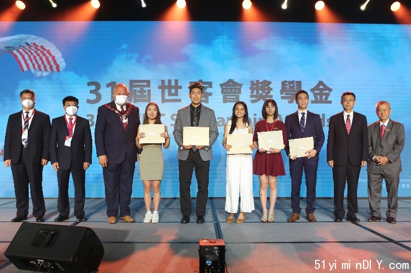 A group of people standing on a stage holding a plaque Description automatically generated with medium confidence